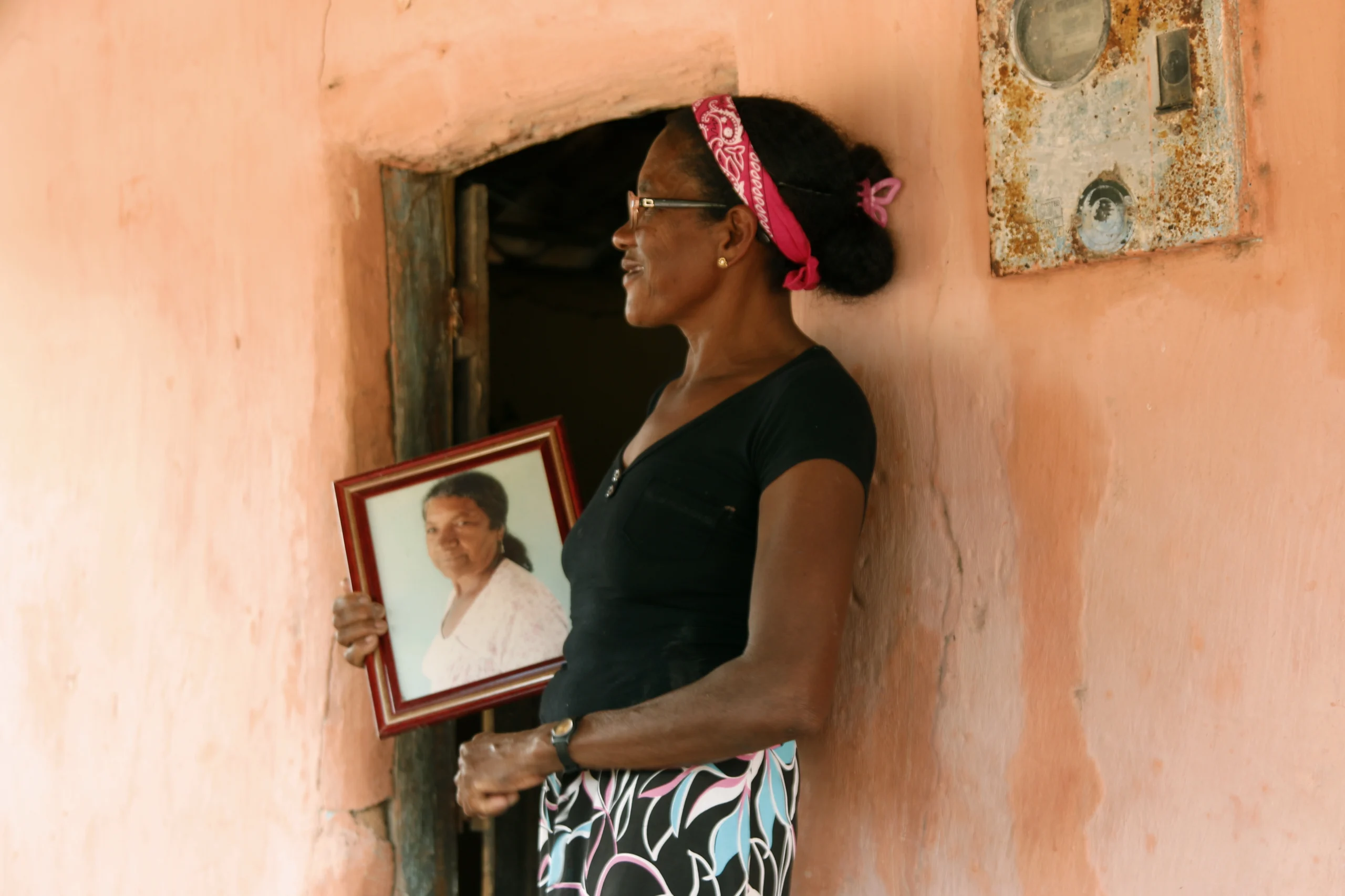 Mulher em frente a casa segurando um quadro de uma mulher
